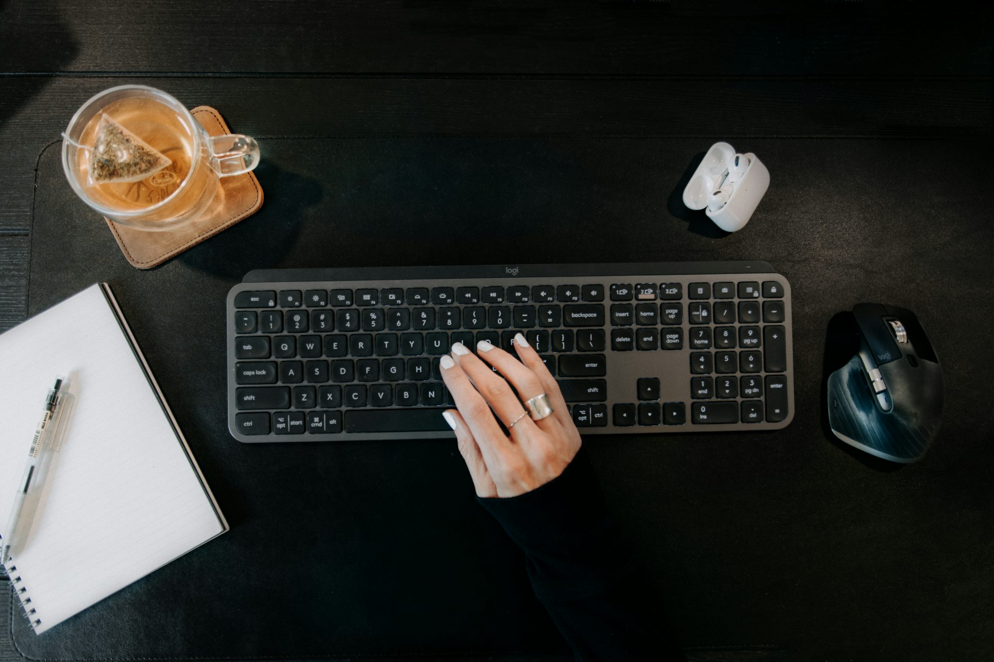 Un poste de rédaction avec clavier, carnet ouvert et tasse de thé